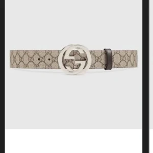 Beige GG-mönstrat bälte från Gucci - Säljer ett beige bälte från Gucci med klassiskt GG-mönster och en stor, rund silverspänne med GG-logga. Bältet har svarta kanter och är gjort i skinn med canvas-yttermaterial. Perfekt accessoar för att lyfta din outfit.