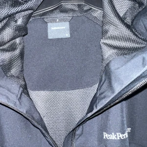 Svart vindjacka från Peak Performance - Säljer en svart vindjacka från Peak Performance med HIPE-teknologi. Jackan har huva, dragkedja framtill och är tillverkad i ett lätt, vatten- och vindtätt material som andas. Perfekt för utomhusaktiviteter och träning.