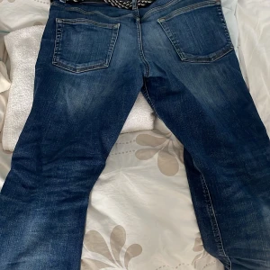 Navy blå jeans - Säljer ett par stil rena as snygga slim fit jeans med slitna detaljer. Byxorna har knäppning med knappar och bakfickor. Perfekta för dig som vill ha en fräsch stil nu i sommar och vår