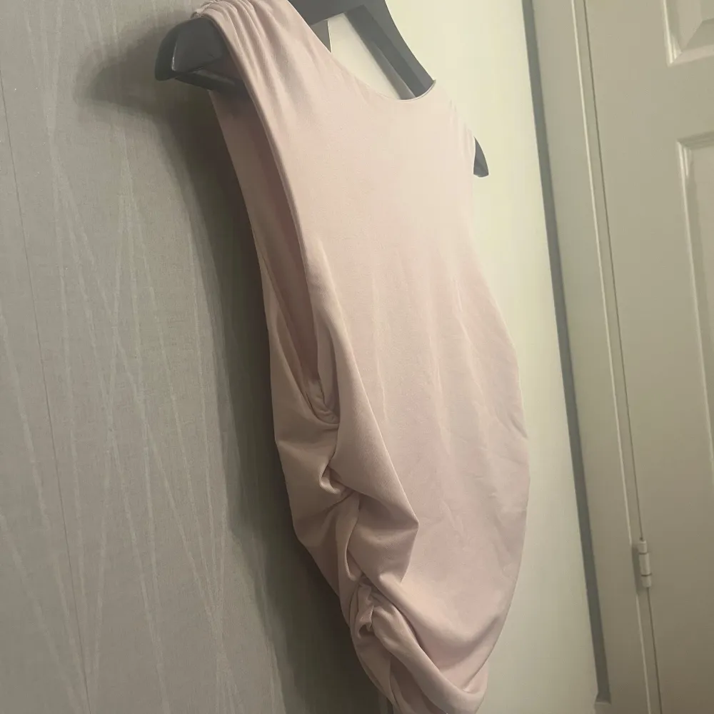 Säljer en ljusrosa ärmlös topp med draperad effekt på sidorna. Toppen har en rund halsringning och är tillverkad i ett mjukt, stretchigt material som ger en snygg passform. Man kan välja både om man vill ha den över eller under naveln. Aldrig använd. Yläosat.