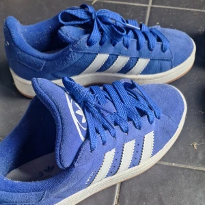 Blå Adidas Campus - Säljer mina par blå Adidas Campus sneakers. Köpte av en tjej på Vinted som hade använt de 1 gång och sen använde jag dem 1 gång också. Så i princip nya. Säljer då de inte riktigt var min stil. Stl 38,5