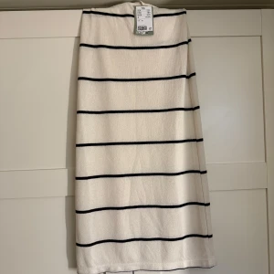Vit och svart randig långkjol från H&M - Säljer en vit långkjol med svarta horisontella ränder från H&M, Helt oanvänd kjol med pris lappen kvar. Materialet känns mjukt och bekvämt mot huden.