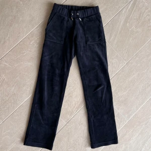 Mörkblåa juicy couture byxor - Säljer ett par mörkblåa juicy couture med raka ben och resår i midjan med snörning. Byxorna har stora fickor fram och bakfickor med knapp. Perfekta för en avslappnad stil. Säljer då de inte kommer till användning.