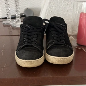 Svarta sneakers i mocka - Säljer ett par svarta sneakers i mocka med svarta skosnören och vit platt sula. Skorna har en klassisk och enkel design som passar till det mesta. Tillverkade i Portugal.