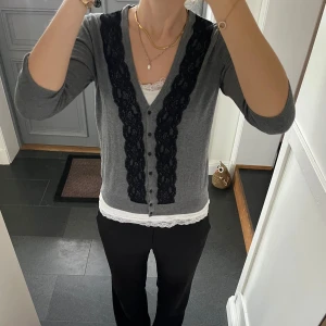Grå stickad kofta  - Trekvartsärmad stickad kofta med svart spets från H&M i storlek S. Fint skick. Använd gärna köp nu!