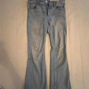 Ljusblå utsvängda jeans från H&M - Säljer ett par ljusblå jeans från H&M med utsvängda ben och justerbar midja. Jeansen har klassiska fickor fram och bak med lock och knapp. Perfekta för dig som gillar retrostil och bekväma jeans. Vi kan diskutera priset☺️