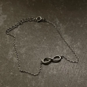 Silverfärgat armband med oändlighetssymbol - Säljer ett tunt och stilrent armband i silverfärg med en oändlighetssymbol i mitten. Justerbar längd med kedja och karbinlås. 