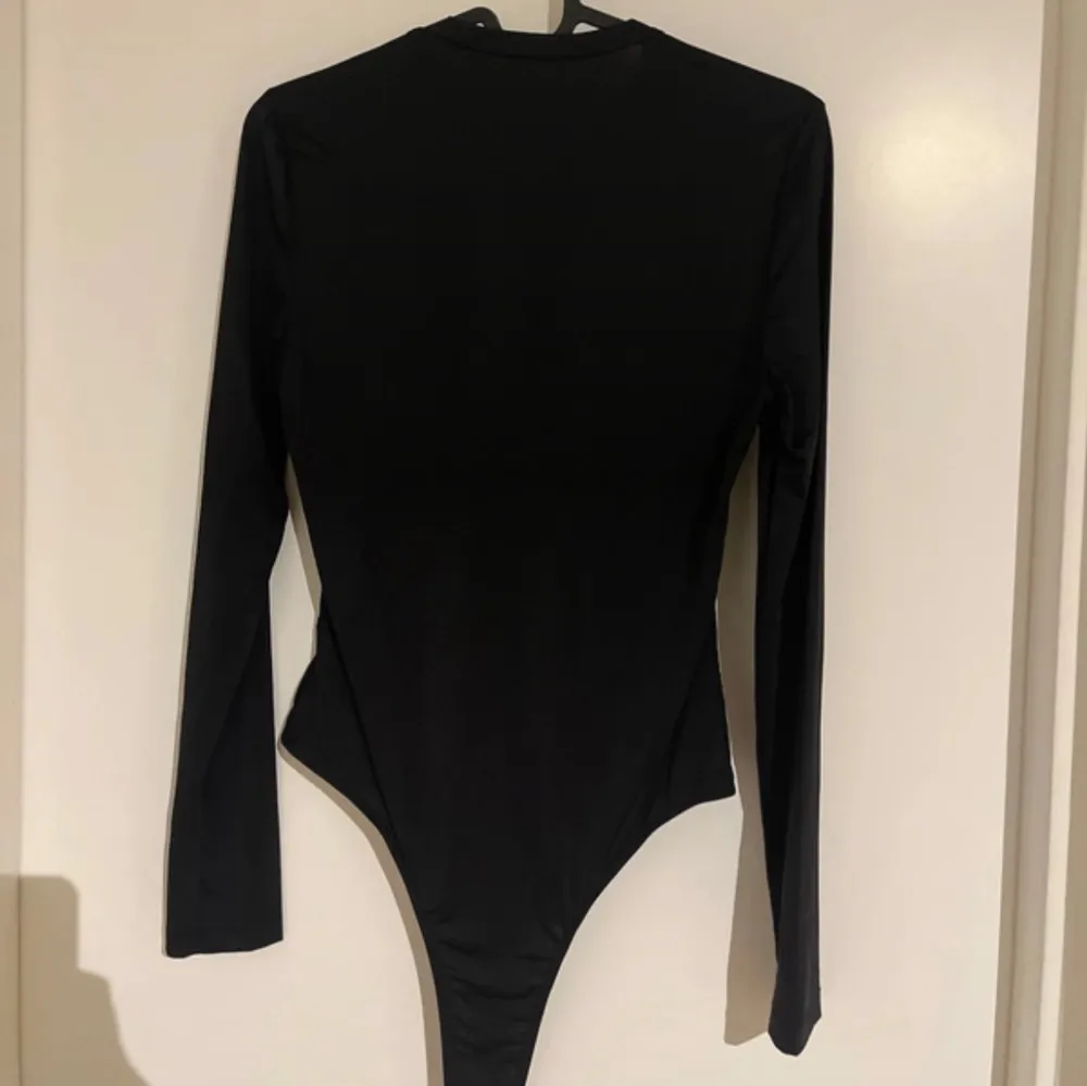 Säljer en svart långärmad bodysuit med rund halsringning. Modellen är tight och har en enkel, stilren design utan synliga detaljer. Perfekt att styla till olika outfits.. Yläosat.