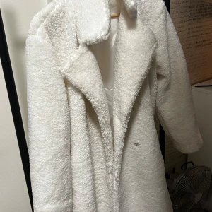 Vit teddyjacka från Bik Bok - Säljer en fluffig och trendig vit teddyjacka från Bik Bok i storlek S. Jackan har lång ärm, bred krage och är helfodrad för extra komfort. Perfekt för att hålla sig varm och snygg under kyliga dagar.