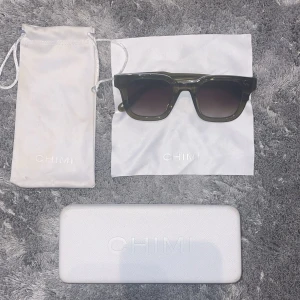 Gröna CHIMI solglasögon 04 - Stilrena gröna solglasögon från CHIMI med fyrkantig form och mörka glas. Bågarna är i transparent mörkgrönt acetat och glasen är tonade. Kommer med vit hård förvaringsbox och tygpåse med CHIMI-logga. Dom är i nyskick utan repor eller liknande. Modell:04. Allt OG medföljer