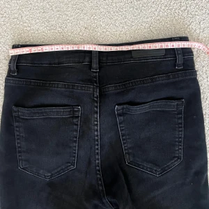 Gråsvarta jeans från Only - Snygga svarta jeans från Only med klassisk femficksdesign och knappgylf. Perfekta för en stilren look. De har en rak passform och är tillverkade i ett stretchigt material för extra komfort.