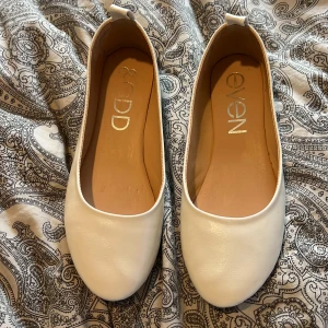 Vita ballerinaskor från Even&Odd - Säljer ett par stilrena vita ballerinaskor från Even&Odd. Skorna har ett väldigt litet märke som syns på ena skon, kontakta mig för fler bilder💛💛🙏🏼 (inget man tänker på) Dem är i st 39 och jag har bara använt dom under mösspåtagning och studenten! Ska rengöra undersidan av skon innan jag skickar skorna. Vid hälen i skon så har det suttit ett inlägg då dom var lite förstora för mig i storleken så därför det ör lite tejp kvar där som jag ska försöka få bort🩷