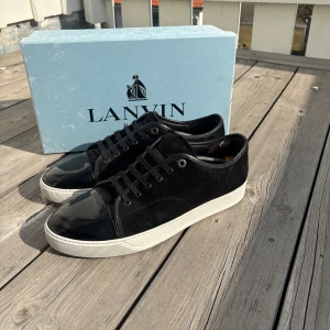 Lanvins uk 10 passar 44/45 - Snygga svarta sneakers från Lanvin med en kombination av mocka och skinn. Skorna har en glansig tå och klassisk snörning. Perfekta för en stilren look. Väldigt bra skick finns en liten defekt som vissas på bilderna utöver det topp skick box tillkommer vid köp dustbag och kvitto finns ej. Priset går att diskutera vid snabb affär men till en viss gräns såklart!