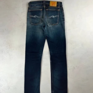 Blå jeans från Nudie - Feta nudie jeans i modellen grim tim. Skicket är 9/10 och originalpris runt 1500kr. Storlek 28:32. Hör av dig vid funderingar!