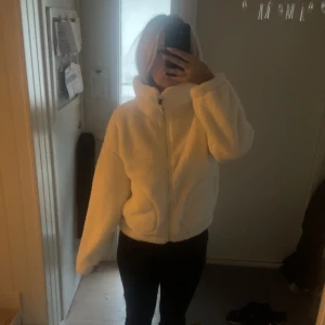 Vit teddyjacka med dragkedja - Mysig vit teddyjacka med dragkedja framtill. Jackan har en hög krage och långa ärmar. Jättebra skick! Är från barnavdelningen men känns som en S! Är slutsåld på hemsidan