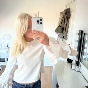 Vit blus  - Säljer en stilren vit blus från Look of the Day med långa ärmar och volangdetaljer. Perfekt för en elegant look. Blusen har en rund hals och är tillverkad i ett mjukt material.
