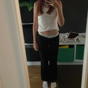 Svarta byxor med spetsdetalj - Snygga svarta byxor med en unik spetsdetalj i midjan. Byxorna har en rak passform och är perfekta för en stilren look. De är tillverkade i ett mjukt och bekvämt material som ger en skön känsla hela dagen. Bootcut