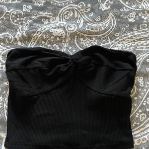 Svart ribbad tubtopp  - Säljer en stilren svart ribbad tubtopp. Toppen har en elegant twistdetalj framtill. 🖤Har använt den en gång men kommer inte till användning längre 💗