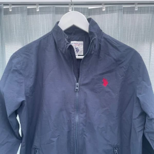 Jacka windbreaker - Säljer nu denna vår jacka från Polo Assn i marinblå | Storlek är 14-15 vilket motsvarar XS i herr storlek, passar ksk 160-170| Skick är 9/10 Inga hål eller defekter bara lite tecken på användning | hör av dig vid funderingar 💭