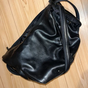 Käsilaukku - Ihana musta nahkainen käsilaukku. Paljon taskuja. Kantohihnan saa avattua vetoketjulla kahdeksi hihnaksi. Kissatalous MMM Mikäli hinta ei miellytä tarjoa rohkeasti Katsothan myös muut ilmoitukseni!!