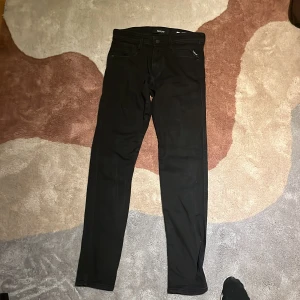 Svarta jeans från Replay - Snygga svarta jeans från Replay med en klassisk femficksdesign. De har en knappgylf och är tillverkade i ett stretchigt material för extra komfort. Perfekta för en stilren look.