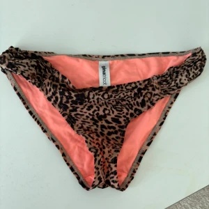 Leopardmönstrad bikiniunderdel från Gina Tricot - Snygg bikiniunderdel från Gina Tricot med leopardmönster och en härlig rosa insida. Perfekt för en dag på stranden eller vid poolen. Den har en klassisk passform och är tillverkad i ett mjukt material för extra komfort.