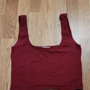 Vinröd linnetopp från NLY Trend - Säljer en snygg vinröd linnetopp från NLY Trend. Toppen har breda axelband och en enkel design som passar perfekt till både vardag och fest. Perfekt för sommardagar eller som ett lager under en jacka.