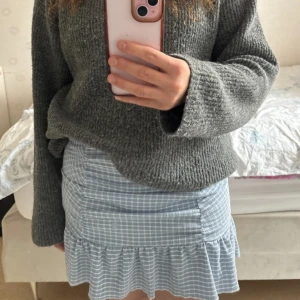 Blå rutig kjol med volang - Charmig blå rutig kortkjol med volangdetaljer. Perfekt för en somrig look med sin lätta och luftiga design. Kjolen har en smickrande passform och är lätt att matcha med olika toppar.