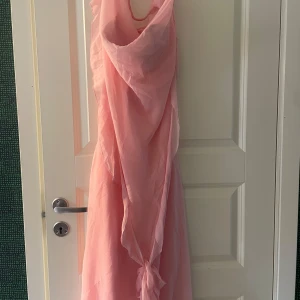Rosa långklänning - Rosa klänning som passar xs s och m, använde 1 gång så i nyskick. Köpte för ca 550. Volangerna är knutna i en rosett men kan knytas upp och ha som på bilden. Köpte från Asos 