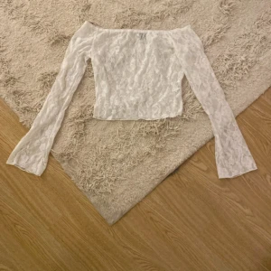Vit spetsblus från Shein - Säljer en elegant vit spetsblus från Shein. Blusen har långa ärmar och en offshoulder-design som ger en romantisk look. Perfekt för att lägga till en touch av elegans till din garderob.