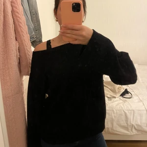Svart stickad tröja - Säljer en svart stickad tröja med en offshoulder-design. Tröjan har långa ärmar och en avslappnad passform, perfekt för en stilren look. Passar bra till både jeans och kjol.