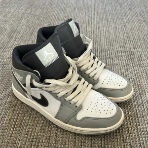 Nike air Jordan 1 smoke gray - Snygga Nike Air Jordans i grått och svart med klassisk snörning och ikonisk logga på sidan. Perfekta för en stilren look med en touch av sportig elegans. Sparsamt använda. Skriv vid minsta fundering 😇.