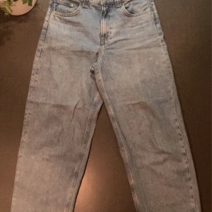 Blå baggy jeans från H&M - Säljer ett par blå baggy jeans från H&M med justerbar midja. Perfekta för en avslappnad stil. De har en klassisk femficksdesign och är tillverkade i denim.