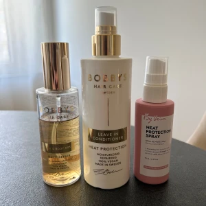 Hårvård från Bobbys & By Léva - Tre hårprodukter: Bobbys Hair & Body Mist i glasflaska med guldlock som är lite använd, helt ny Bobbys Leave In Conditioner i vit plastflaska med guldpump och helt ny By Léva Heat Protection Spray i rosa plastflaska. Alla med pumpfunktion och stilren design.