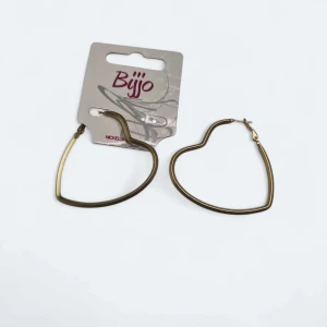 Guldiga hjärtformade örhängen Bijjo - Stora, hjärtformade örhängen i guldig metall från Bijjo. De har en tunn, stilren design och är både nickel- och blyfria. Perfekta för dig som vill ha ett statement-smycke med romantisk vibe.