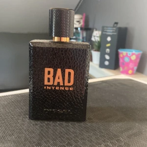 Diesel BAD Intense parfym - Diesel BAD Intense är en herrparfym i en svart, fyrkantig flaska med läderliknande struktur och kopparfärgade detaljer. Flaskan har en robust känsla och lock med mönstrad yta. Doften är känd för sin intensiva doft