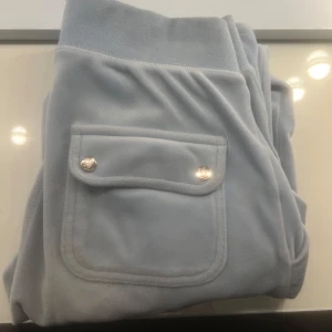 Säljer Ljusblå juicy byxor XS  - Säljer ett par ljusblå juicy byxor med low waist. Byxorna har snygga fickor bak. Perfekta för en chill och avslappnad stil. 