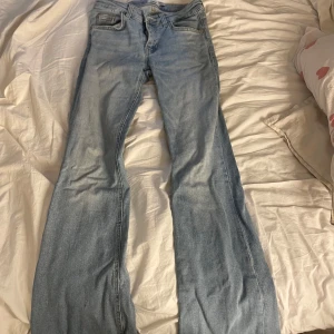 Ljusblå bootcut jeans - Säljer ett par ljusblå jeans med bootcut-modell. Jeansen har klassisk femficksdesign, normal passform och är tillverkade i mjukt denimtyg. Perfekta för dig som gillar retrovibbar och vill ha ett par snygga jeans med utsvängda ben.