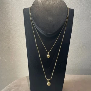  Guldigt Ioaku  halsband med kulkedja och boll - Stilrent halsband i guldton med kulkedja och rund bollformad berlock. Halsbandet har en minimalistisk och modern design som passar perfekt för att lyfta vilken outfit som helst. Kedjan är tunn och smidig, och bollen ger ett snyggt statement. Helt ny med prislapp på! 🌺