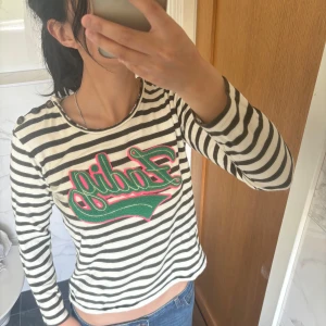 Zadig Randig långärmad tröja med tryck - Säljer en vit och svart randig långärmad tröja med grönt och rött broderat tryck framtill. Från Zadig Voltaire 