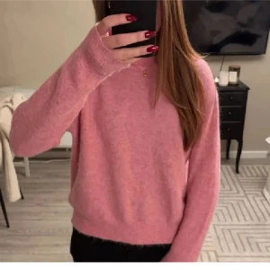 Rosa stickad tröja med rund hals - Mysig rosa stickad tröja med rund halsringning och långa ärmar. Tröjan har en enkel och clean look med ribbade muddar vid ärmslut och nederkant. Perfekt för dig som gillar en chill och stilren vibe.