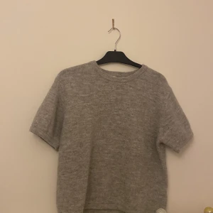 Grå stickad kortärmad tröja - Mysig grå stickad tröja med korta ärmar och rund hals. Från Gina Tricot den är i storlek 170 Young men jag som S passar i den  den är andvänd cirka en gång 