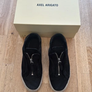 Axel arigato skor - Svarta arigato 90 zip i använt skick men mycke kvar storlek 41 . Inte orginalsulor innuti och boxen följer inte med, skorna säljs inte längre 