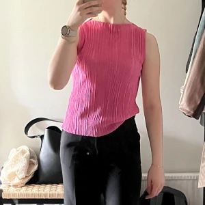 Rosa plisserad ärmlös topp - Säljer en snygg rosa ärmlös topp med plisserad struktur. Toppen har rak halsringning och en rak passform.