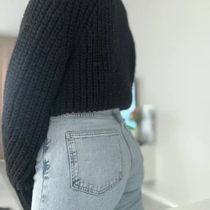 Svart stickad polotröja - Säljer en svart, chunky stickad polotröja med hög hals och långa ärmar. Tröjan har en loose passform och är perfekt att styla med jeans för en cool och avslappnad look. Den grova ribbade strukturen ger en trendig vibe.