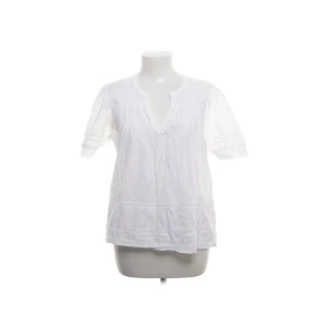 Vit blus - Luftig vit blus från Scotch & Soda med korta ärmar och v-ringad hals. Blusen har fina veckdetaljer framtill och spetsinslag på ärmarna och nertill. Perfekt för en fräsch och avslappnad look under varmare dagar🤍