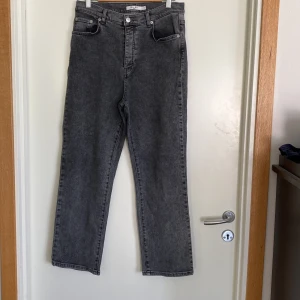 Gråa raka jeans från NA-KD stretch stl 40 - Snygga grå jeans från NA-KD med hög midja och raka ben. Jeansen har klassisk femficksdesign, bälteshällor och knappgylf. Materialet är denim i bomull och färgen är tvättad grå för en cool vintagekänsla.