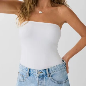 Vit bandeau tubtopp i bomull - Säljer en stilren vit bandeau tubtopp i mjuk bomull. Toppen är ärmlös och axelbandslös med tight passform och ribbad struktur. Perfekt att matcha med jeans eller kjol för en clean look. Enkel och fräsch design som funkar till många outfits. Helt ny med prislapp🤍