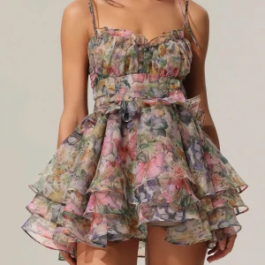 Bellabarnett klänning  - Supersöt kort klänning med blommigt och fjärilsmönster i pastelliga färger. Volanger, smala axelband med knyt och snörning i ryggen som är lite korsett aktigt.💞💞helt oanvänd, ordninarie pris: 1200kr.