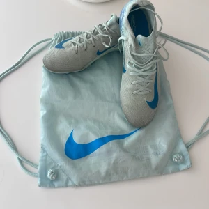 Nike Mercurial fotbollsskor ljusblå - Säljer ett par Nike Mercurial fotbollsskor i ljusgblått  med blå detaljer och snörning. Skorna har en smal passform, platt sula med dobbar och är tillverkade i syntetmaterial. Perfekta för dig som vill sticka ut på planen! Levereras med matchande Nike-påse./ nästan helt nya använda. Två gånger pris kan diskuteras 